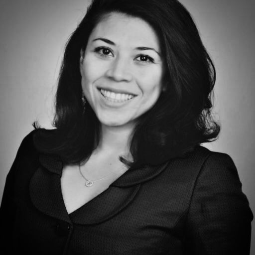 Black and white portrait of a woman with shoulder-length hair smiling, wearing a dark blazer.