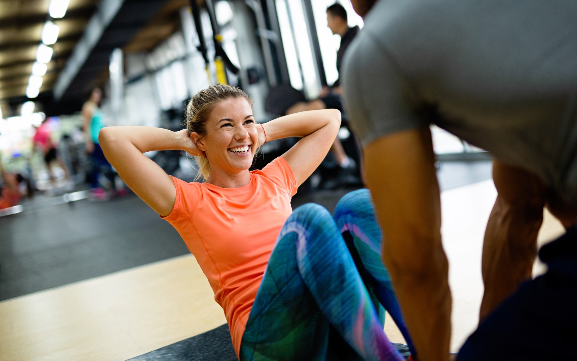 Fit happy woman with her personal fitness trainer in the gym exercising with dumbbells